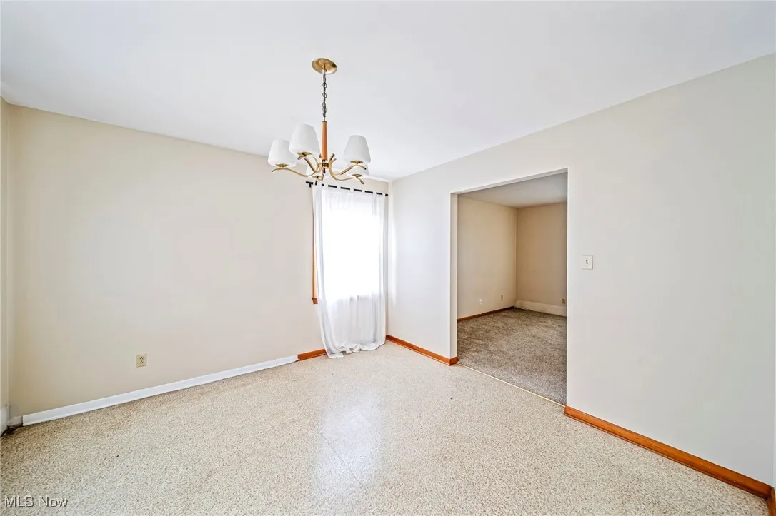 Spare room with a chandelier and baseboards