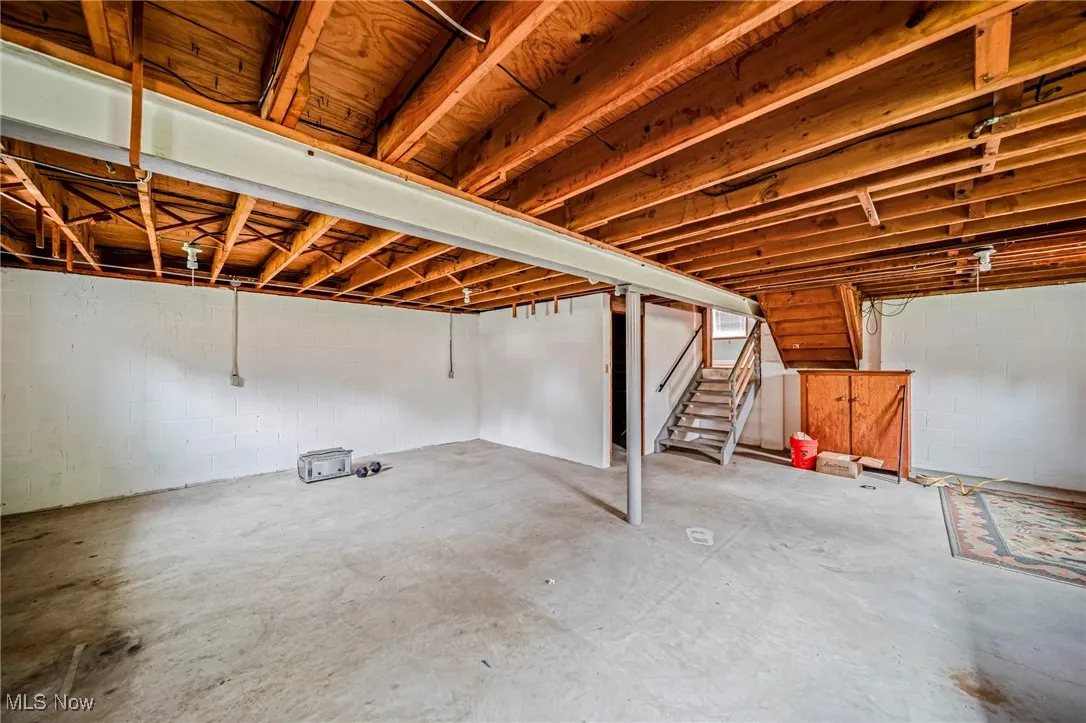 Unfinished below grade area with stairs and concrete block wall