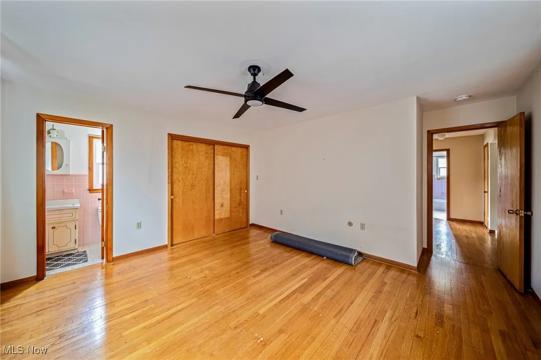 Unfurnished bedroom with light wood-style flooring, a closet, baseboards, and a ceiling fan