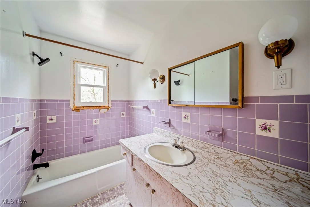 Bathroom featuring tile walls, vanity, and wainscoting