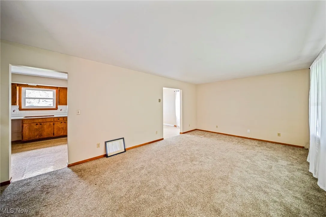 Carpeted spare room featuring baseboards