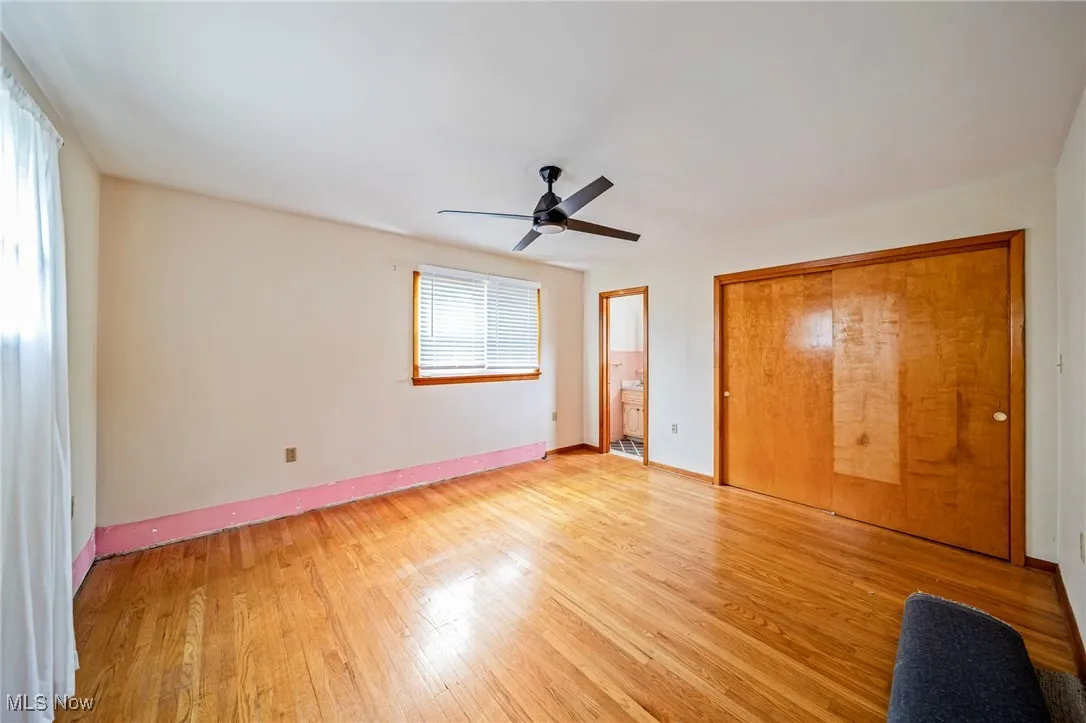 Unfurnished bedroom featuring light wood-type flooring, baseboards, ensuite bath, a closet, and a ceiling fan