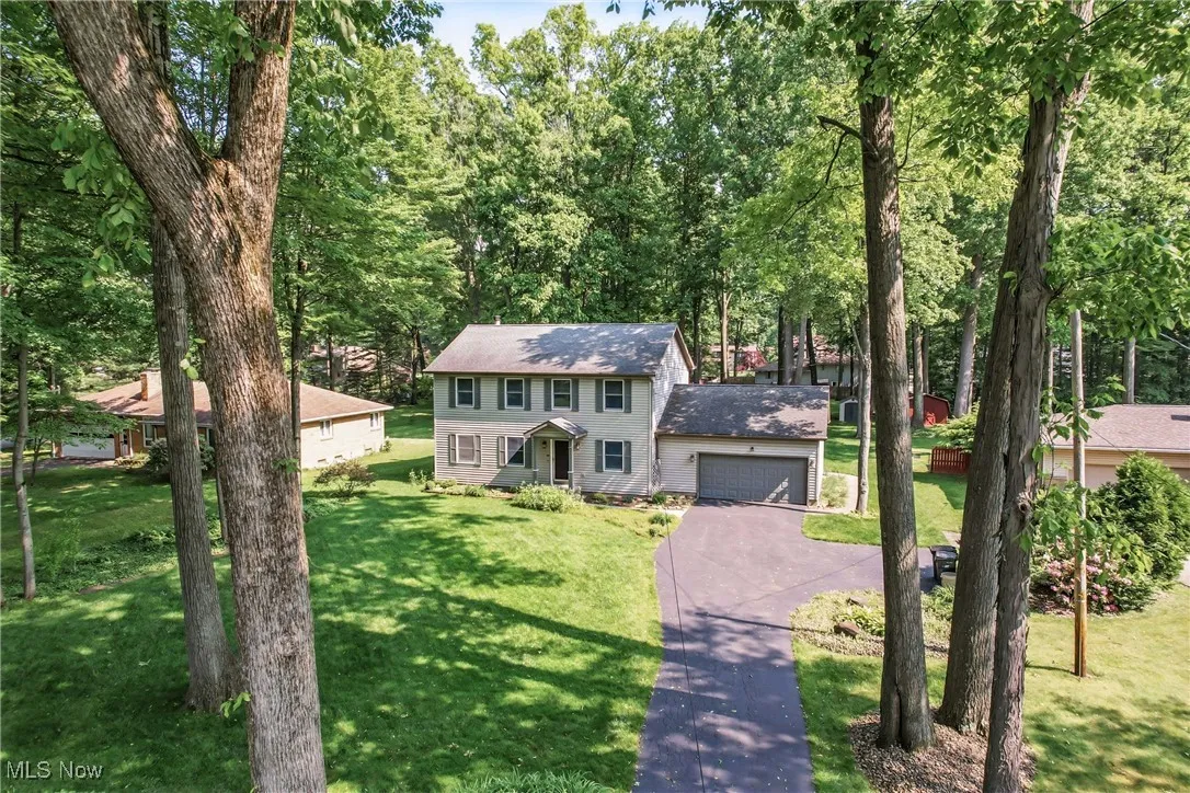 Colonial-style house with asphalt driveway, a front lawn, and an attached garage