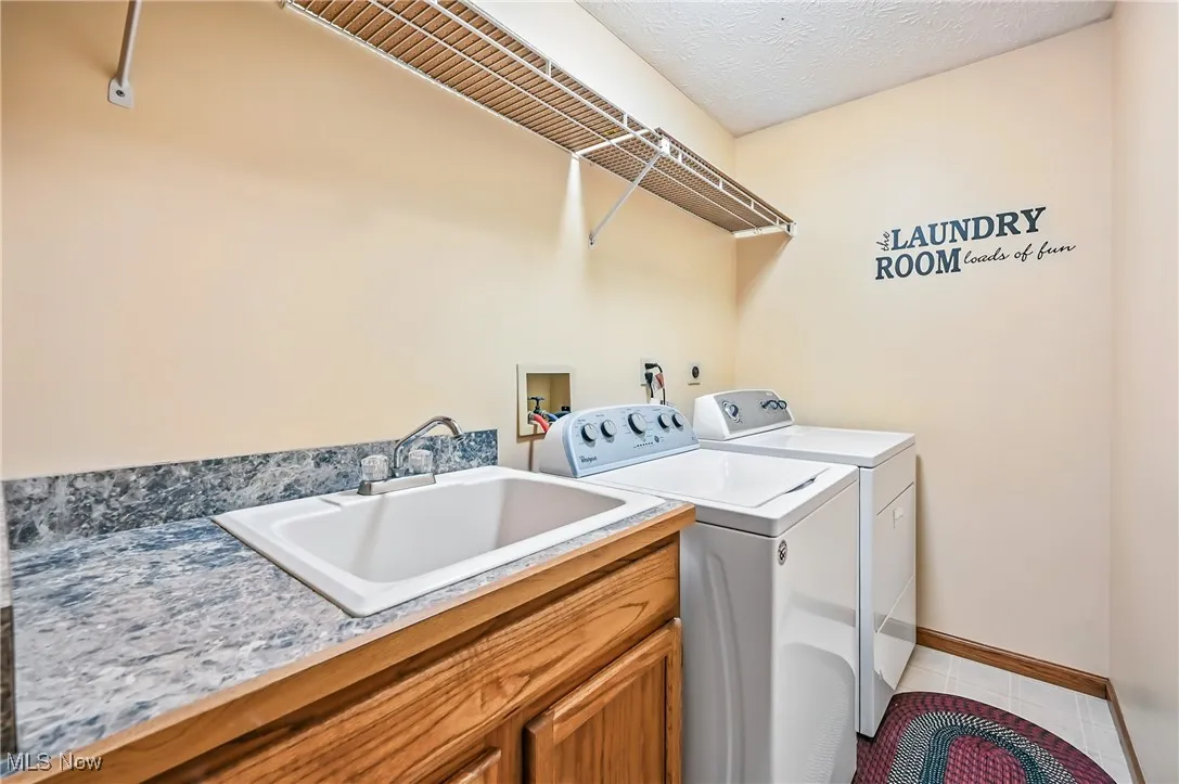 Washroom featuring washing machine and dryer, tile patterned flooring, cabinet space, and baseboards