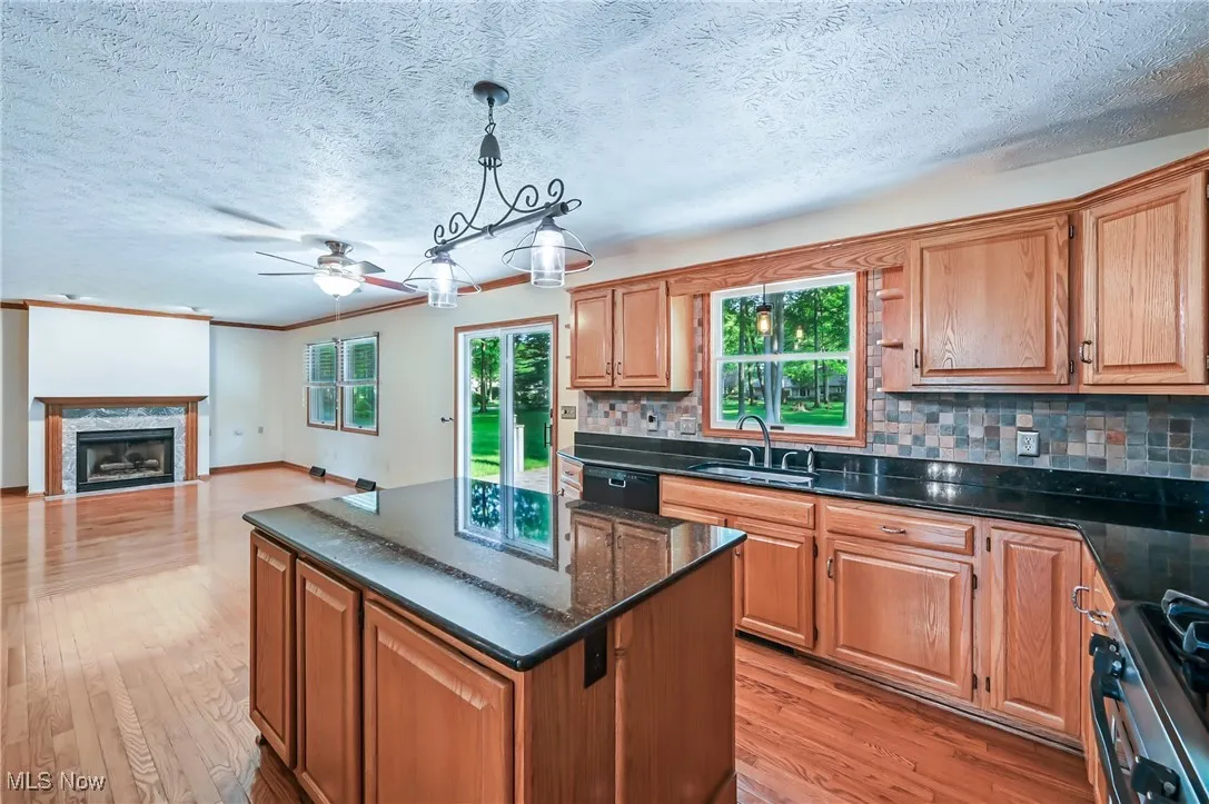 Kitchen with a sink, ceiling fan, light wood-type flooring, tasteful backsplash, and range