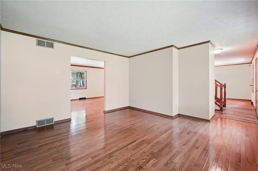 Living room with ornamental molding, wood finished floors, stairway, a textured ceiling, and baseboards