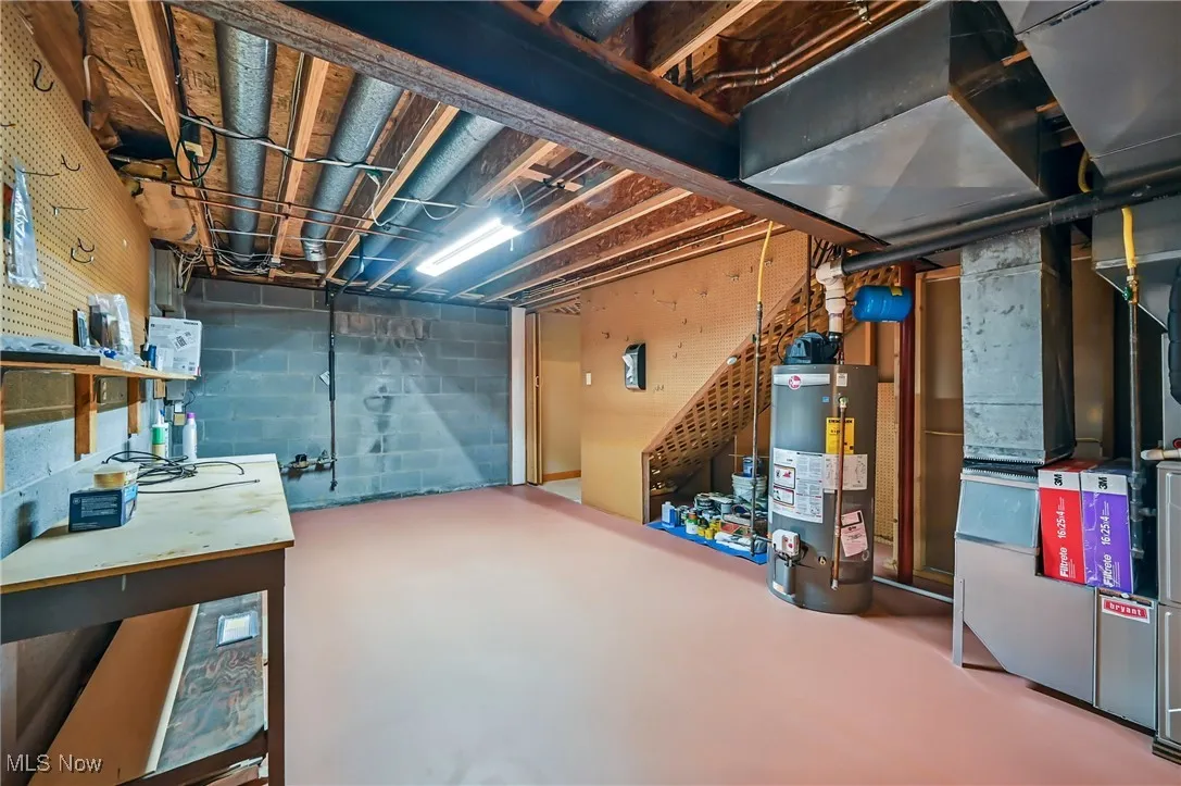 Unfinished below grade area with water heater, heating unit, and a workshop area
