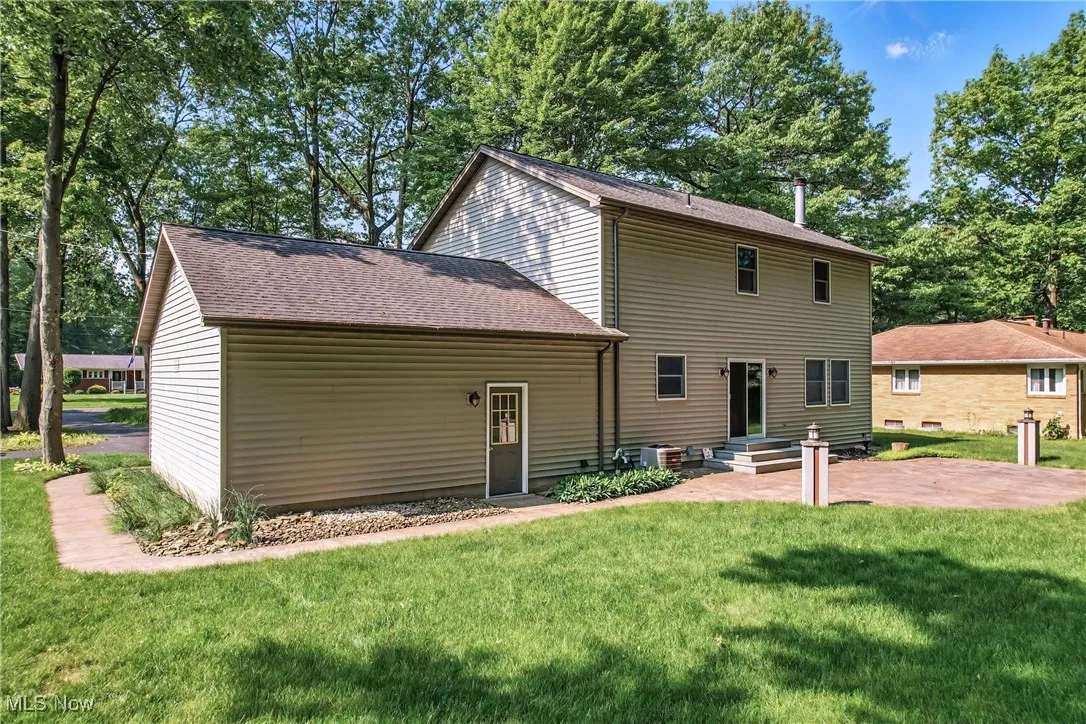 Back of property featuring a lawn, a patio area, and roof with shingles