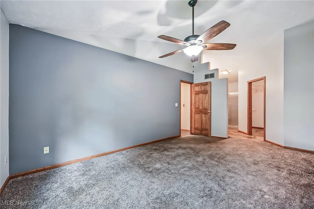 Primary bedroom with carpet floors, baseboards, vaulted ceiling, and ceiling fan
