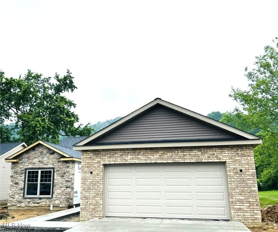View of front of home with driveway, an attached garage, and brick siding