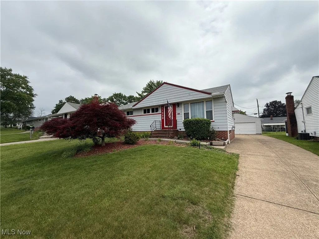 View of front facade with an outdoor structure, a front yard, a garage, and central AC