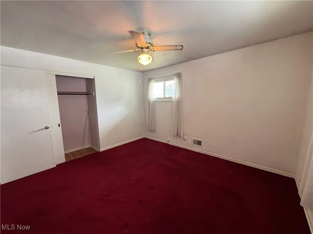 Unfurnished bedroom featuring carpet flooring, a closet, baseboards, and a ceiling fan
