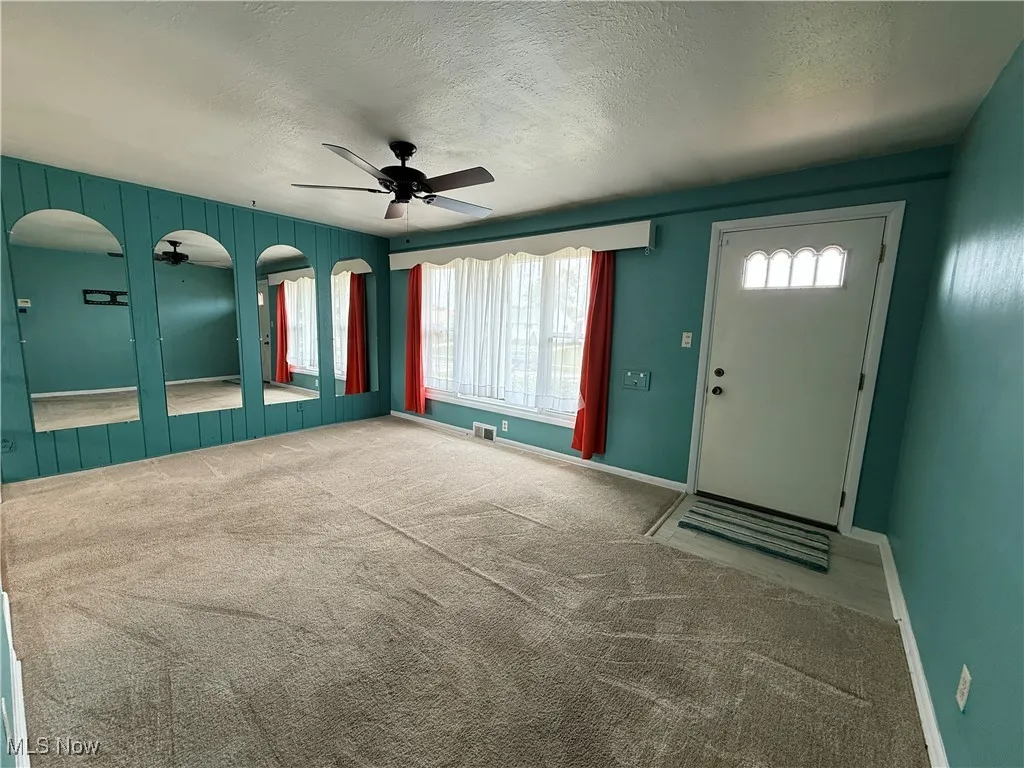 Carpeted entryway with ceiling fan, a textured ceiling, baseboards, and arched walkways