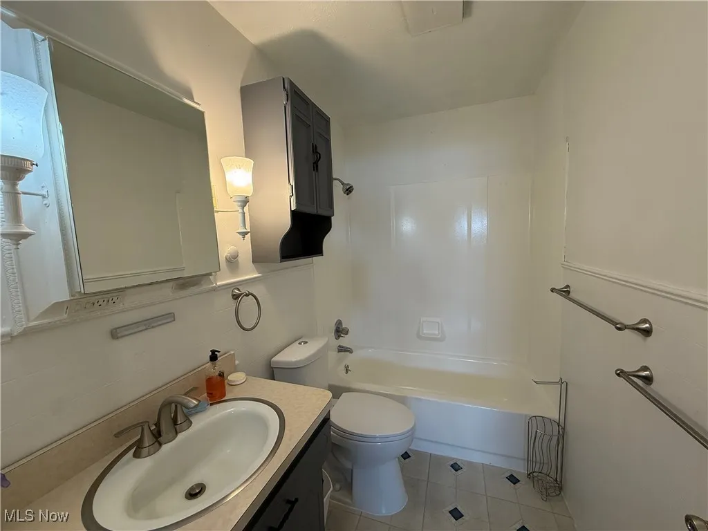Bathroom featuring toilet, vanity, tile patterned floors, and bathing tub / shower combination