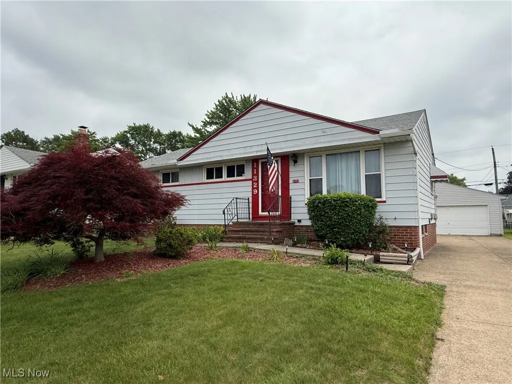View of front facade with a front yard, an outdoor structure, a garage, a shingled roof, and entry steps