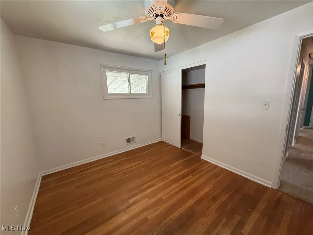 Unfurnished bedroom featuring wood finished floors, baseboards, and a closet