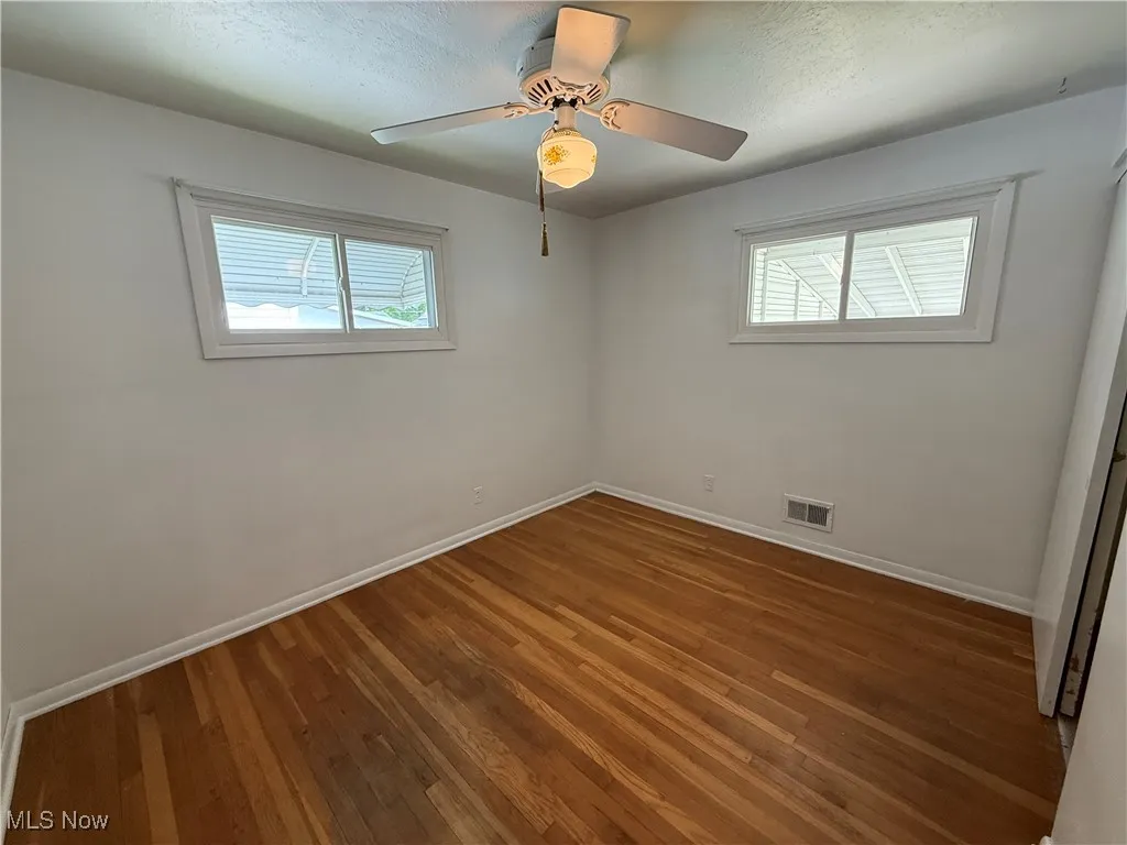 Empty room featuring healthy amount of natural light, baseboards, and wood finished floors