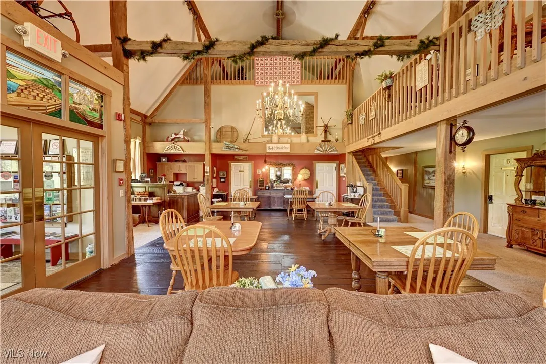 Living room featuring a towering ceiling, a chandelier, stairs, hardwood / wood-style flooring, and french doors