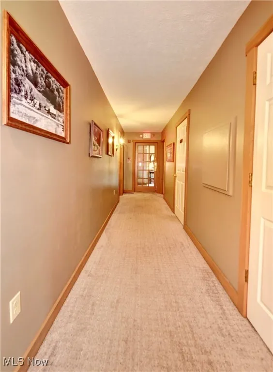 Hall with light carpet, baseboards, and a textured ceiling