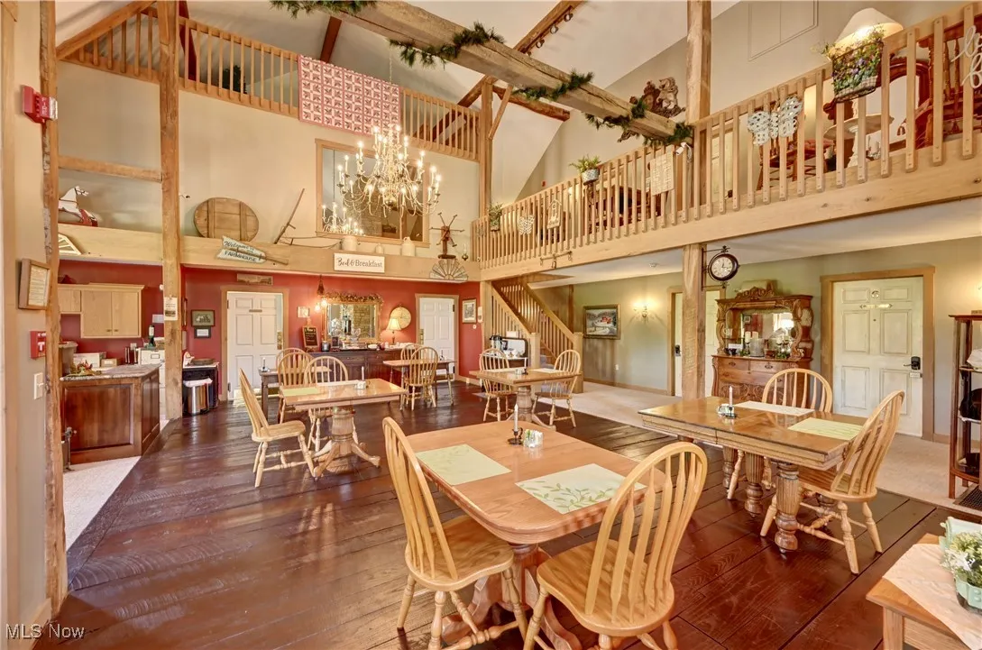 Dining area featuring a towering ceiling, wood-type flooring, a chandelier, and stairway