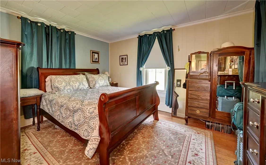 Bedroom featuring wood finished floors and crown molding