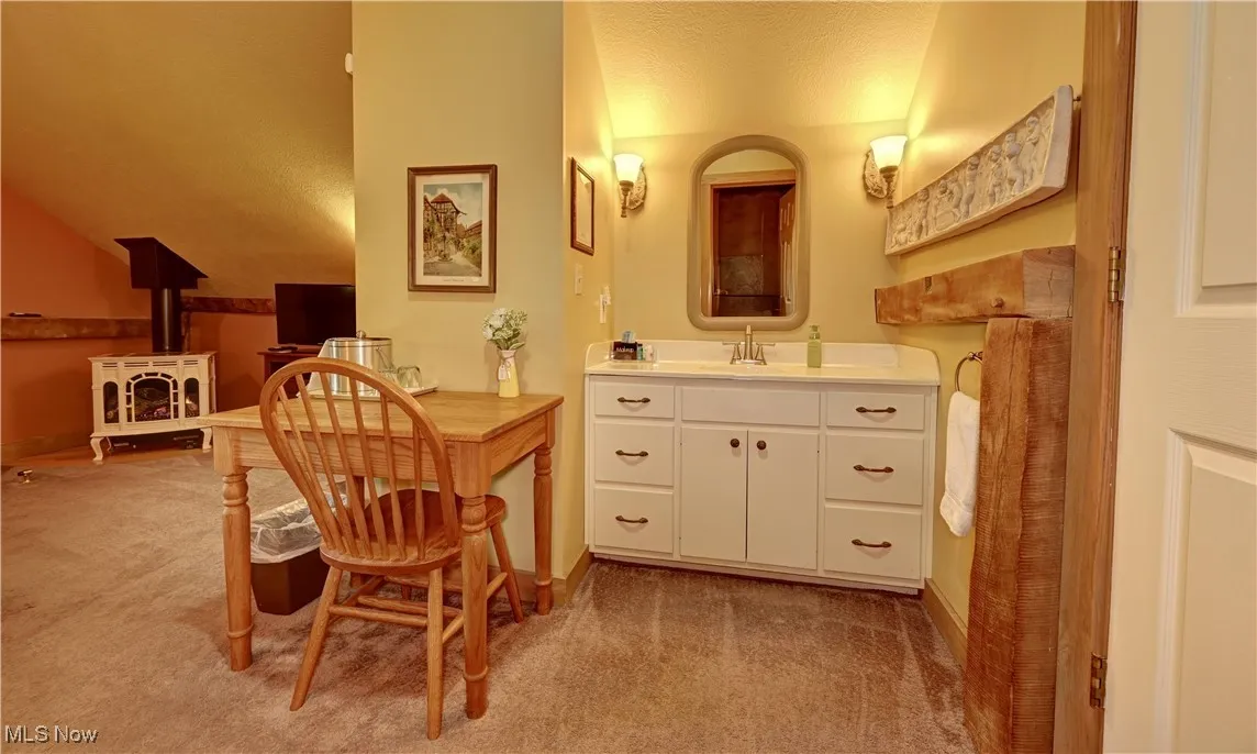 Bathroom with vanity, a textured ceiling, baseboards, and vaulted ceiling