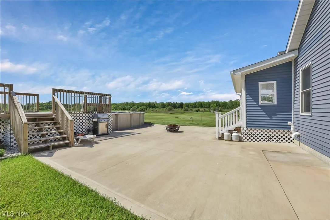 View of patio / terrace with stairs, a wooden deck, and an outdoor fire pit