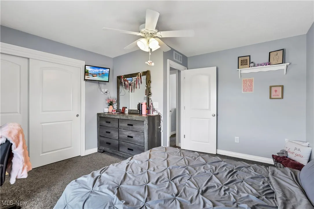 Bedroom with carpet, baseboards, ceiling fan, and a closet