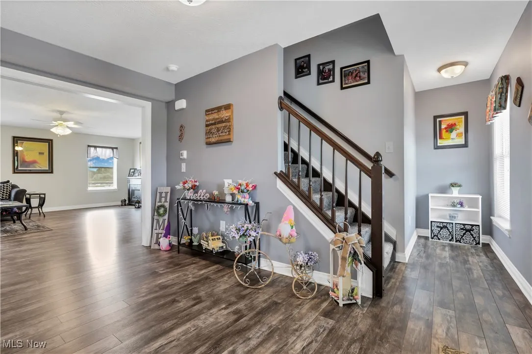 Foyer entrance with dark wood-type flooring, baseboards, stairs, and ceiling fan