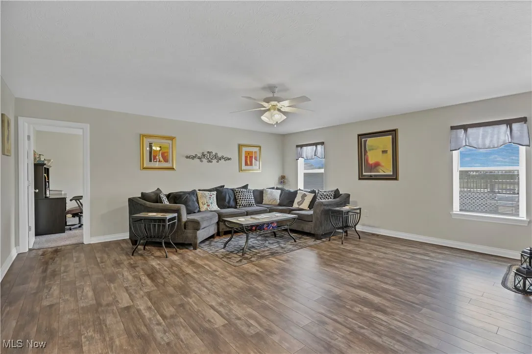 Living room featuring dark wood finished floors, a ceiling fan, and baseboards