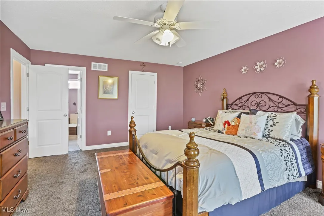 Bedroom with carpet, baseboards, ensuite bath, and ceiling fan