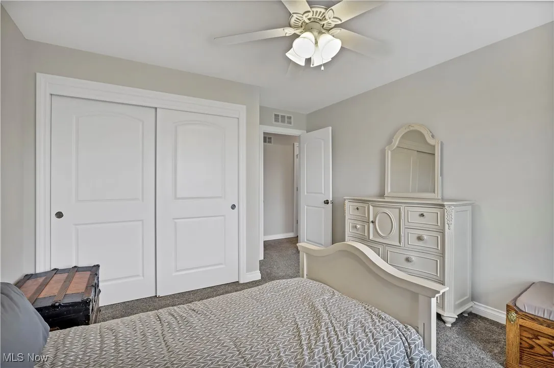 Bedroom with dark colored carpet, baseboards, a closet, and ceiling fan