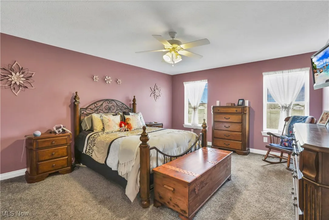 Carpeted bedroom featuring ceiling fan and baseboards