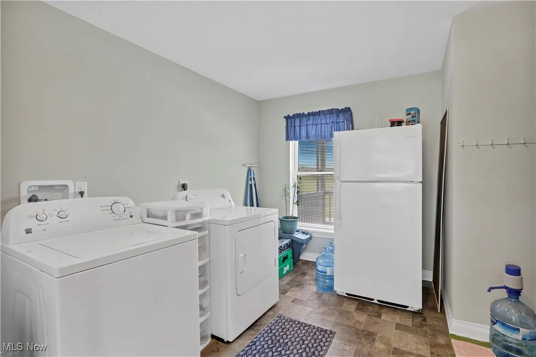 Laundry area with washer and dryer, baseboards, and stone finish floors