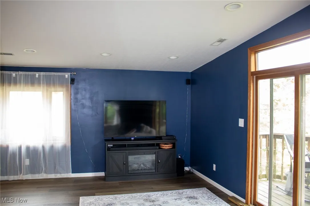 Unfurnished living room with wood finished floors, baseboards, and recessed lighting