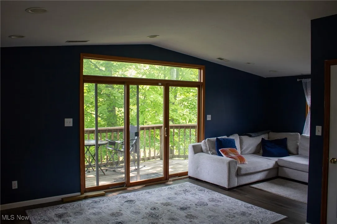 Living room with lofted ceiling, wood finished floors, and baseboards