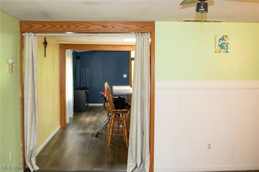 Hall featuring dark wood finished floors and wainscoting
