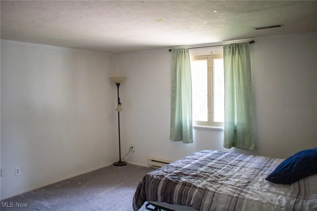 Bedroom with carpet flooring and baseboard heating