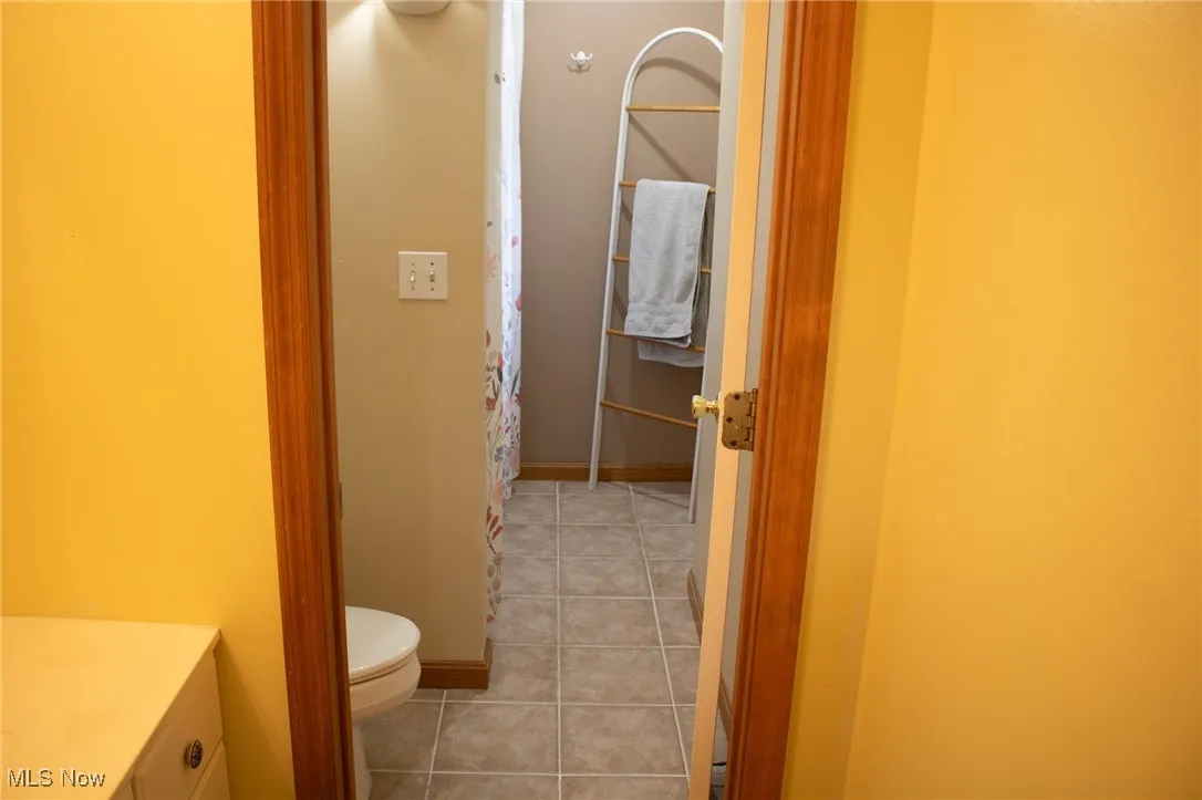 Bathroom with toilet, vanity, tile patterned flooring, baseboards, and curtained shower
