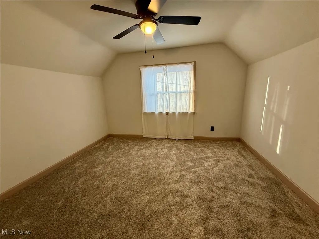Additional living space featuring lofted ceiling, ceiling fan, and light carpet