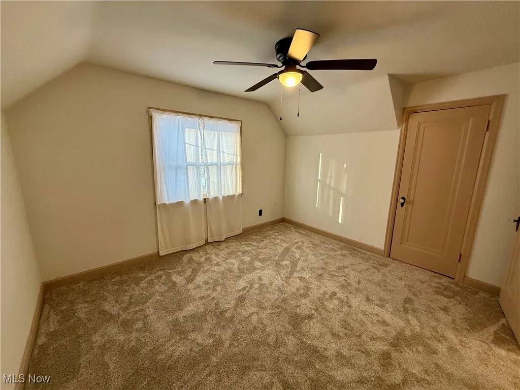 Bonus room with vaulted ceiling, ceiling fan, and light carpet
