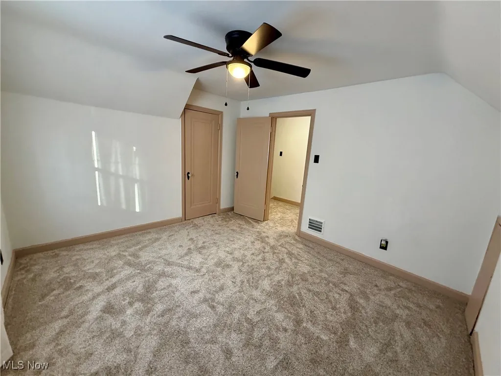 Additional living space featuring ceiling fan, lofted ceiling, and light colored carpet