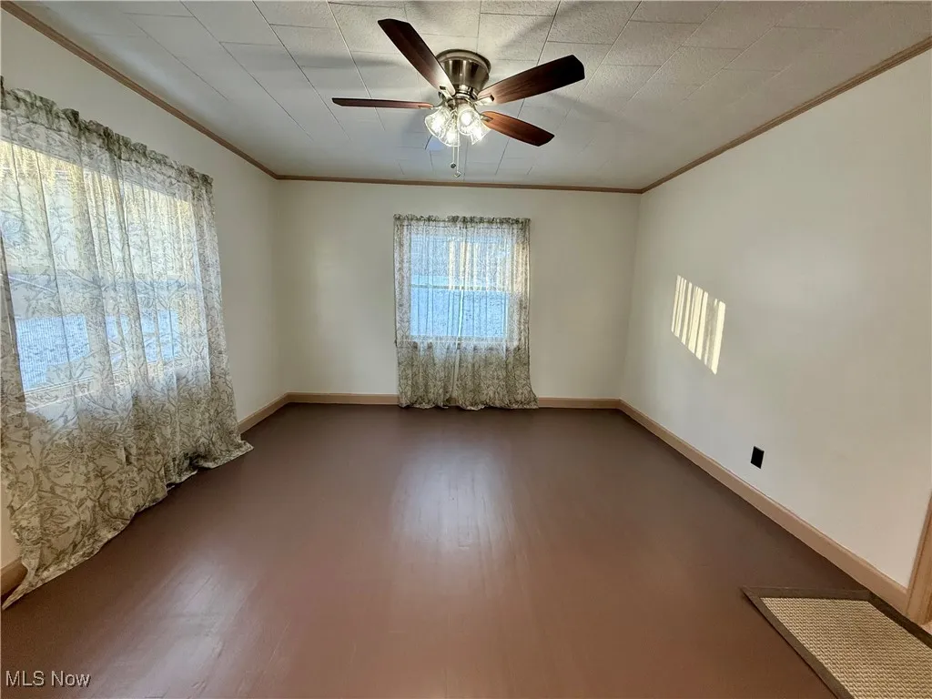 Empty room featuring ceiling fan, crown molding, and hardwood / wood-style floors