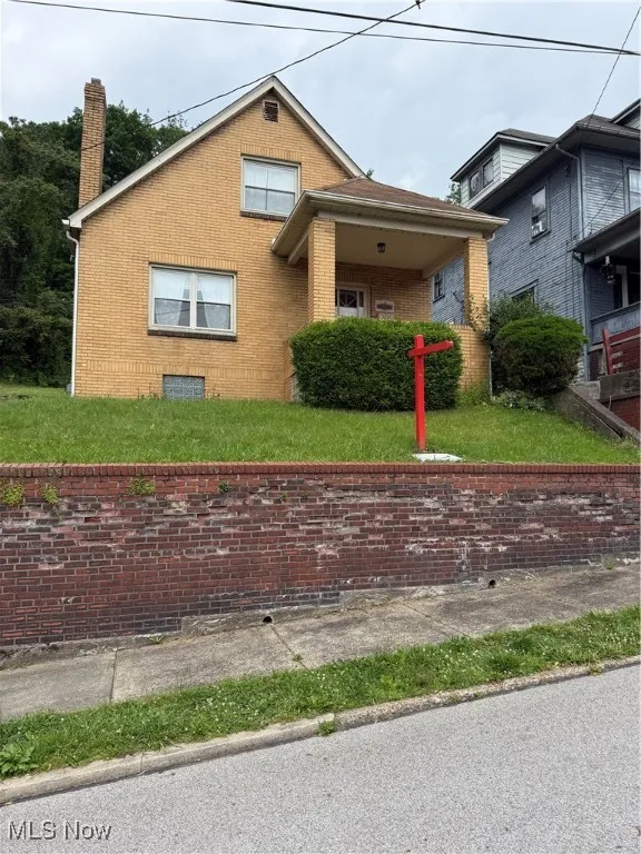 View of front of house with a chimney, brick siding, and a front lawn