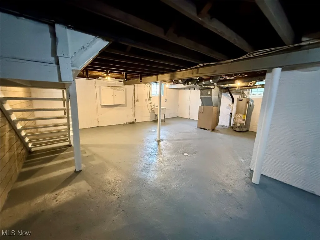 Basement featuring sink, heating unit, and gas water heater