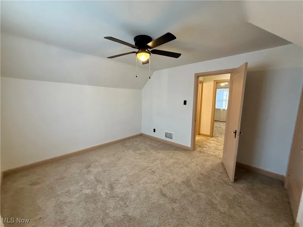 Additional living space featuring vaulted ceiling, ceiling fan, and light colored carpet