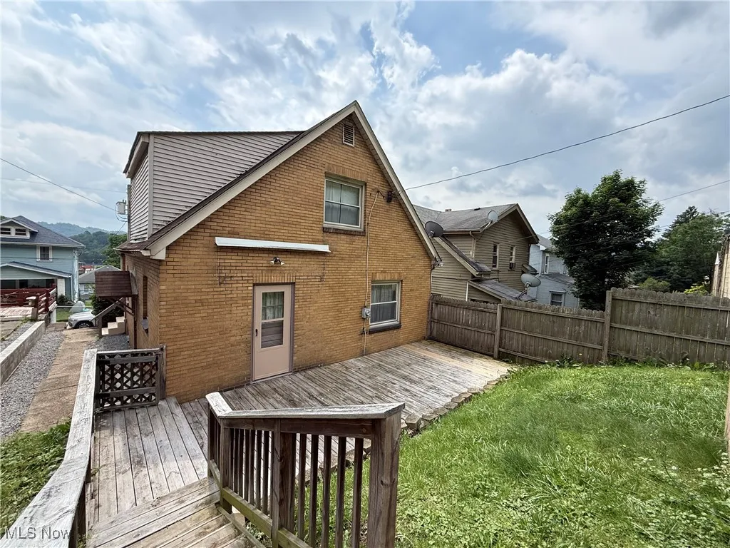 Back of property featuring brick siding and a wooden deck