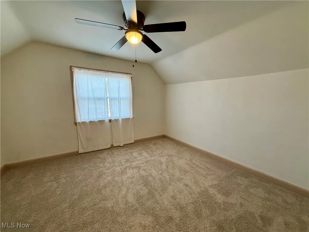 Bonus room with ceiling fan, light carpet, and lofted ceiling