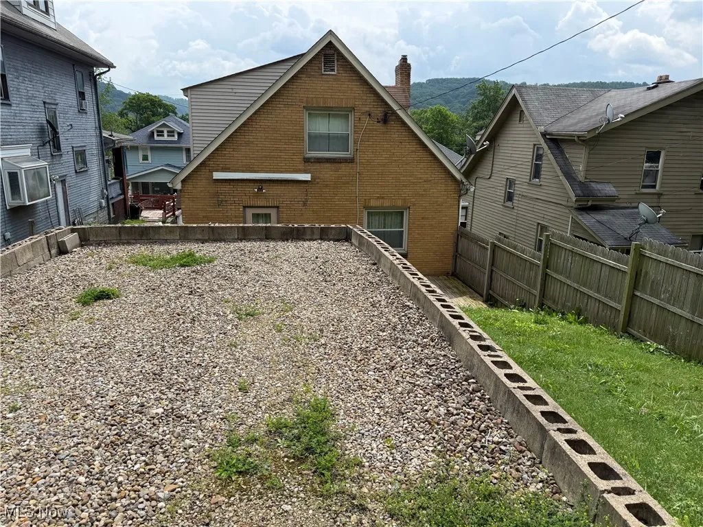 Back of property featuring a chimney, a fenced backyard, and brick siding