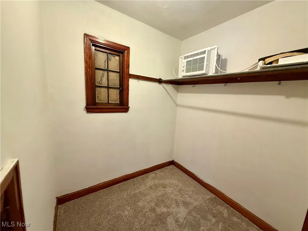 Spacious closet featuring carpet floors and a wall mounted air conditioner